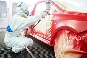 auto mechanic worker painting a red car in a paint chamber during repair work